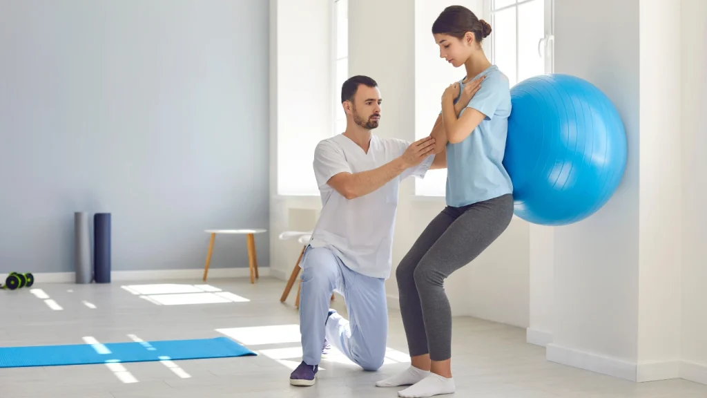 Physiotherapist assisting a woman with balance exercises using a stability ball—demonstrating the benefits of physiotherapy for mobility and strength recovery.