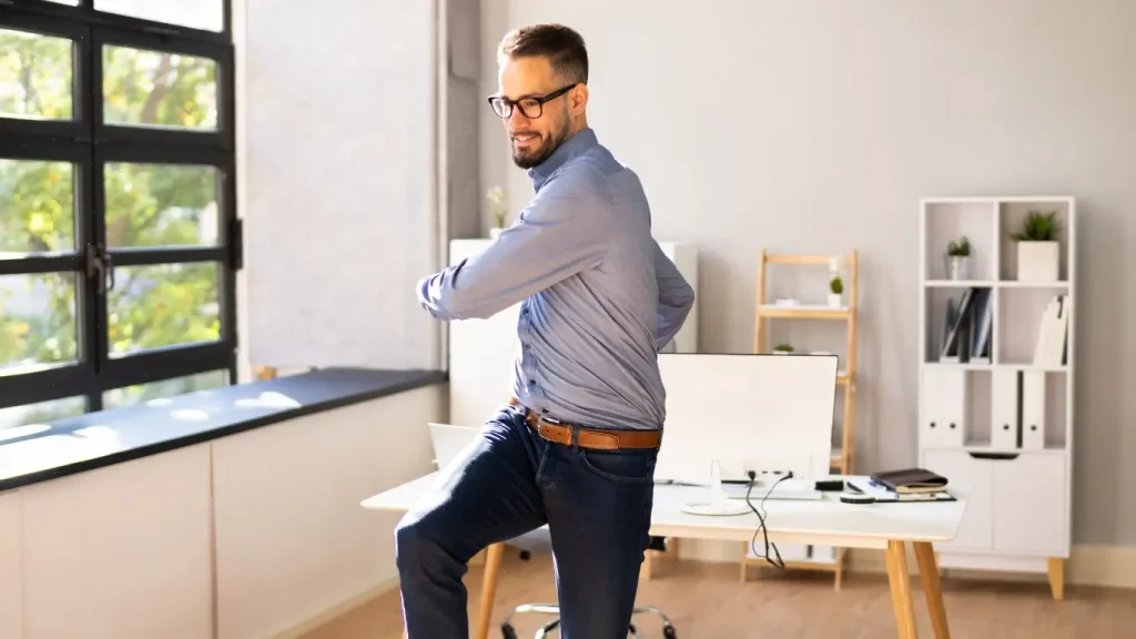 Workplace injury rehabilitation – employee stretching at desk to prevent strain